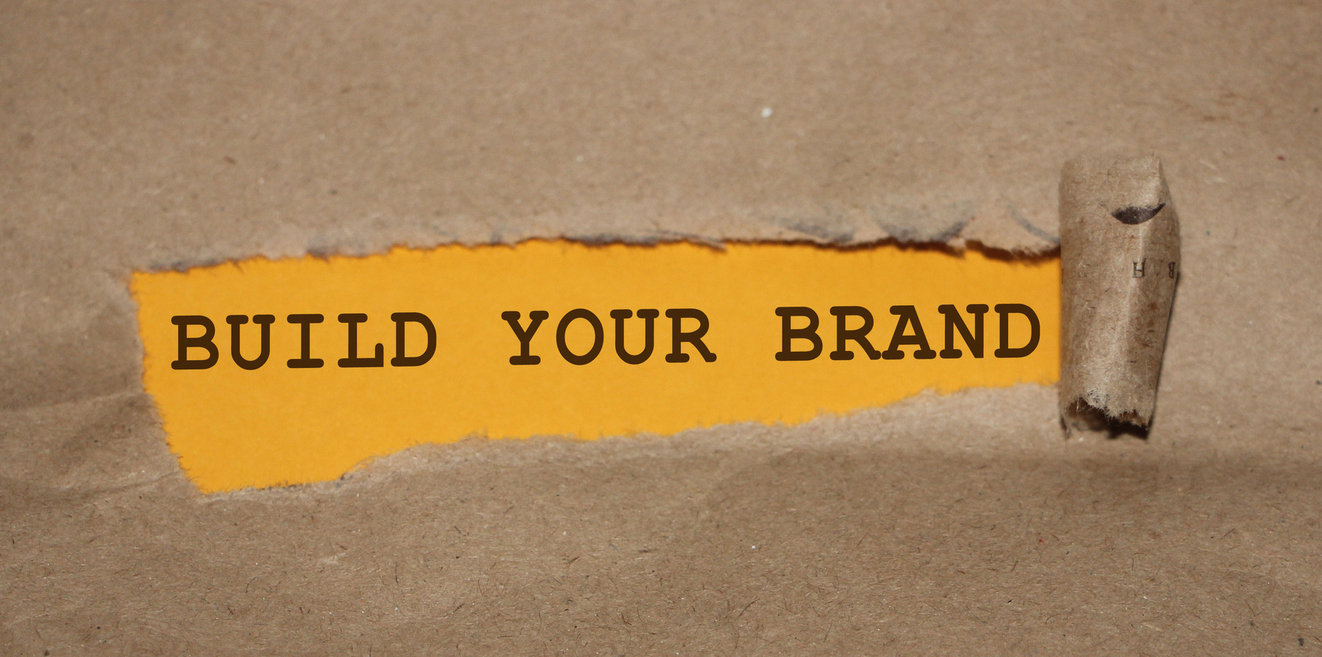 BUILD YOUR BRAND message written under torn paper. Branding rebranding marketing business concept